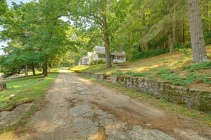 A stone pathway leading to a white house with a porch, surrounded by trees and greenery. - Saddle Up! Belleview Farm Stay w/ Pool & Stables (Belleview)