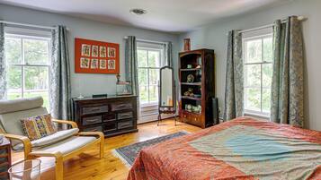 A room with a bed, a chair, a dresser, a bookshelf, and a window with curtains.