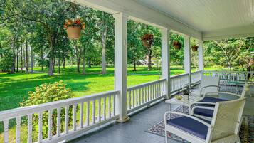 A covered porch with white railings, wicker furniture, and hanging flower baskets.