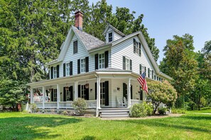 A two-story house with a porch, a chimney, and an American flag. - Historic Riverfront Escape in Youngstown w/ Dock (Youngstown)