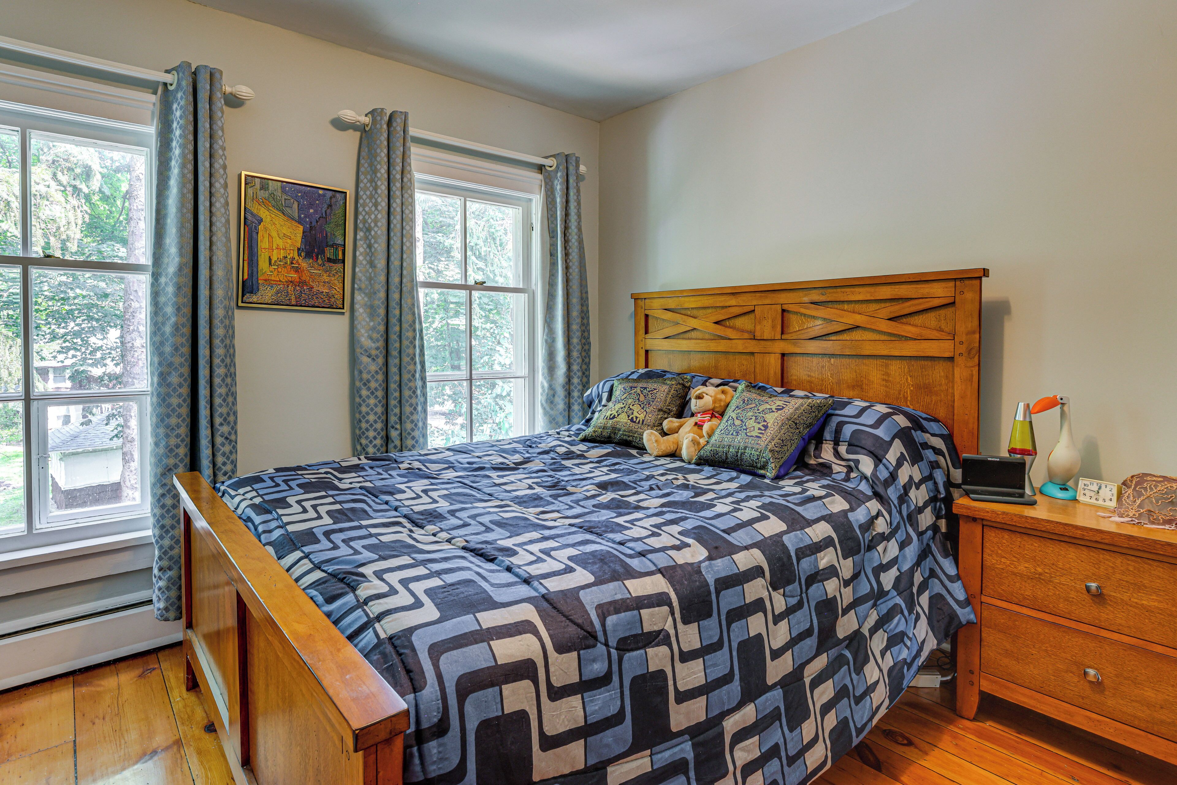 A bedroom with a bed, a wooden headboard, a nightstand, a lamp, and a clock.