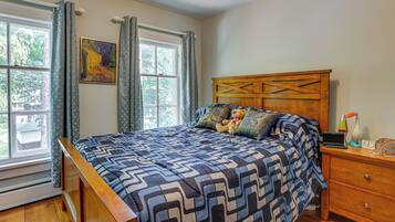 A bedroom with a bed, a wooden headboard, a nightstand, a lamp, and a clock.