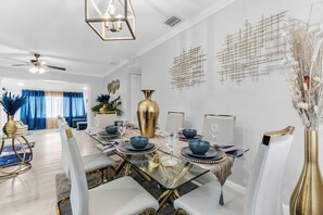 Un'area pranzo moderna con tavolo in vetro, dettagli dorati e un elemento decorativo a parete.