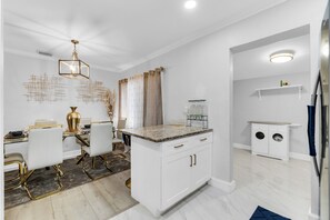 A modern kitchen with white cabinetry, a granite countertop, and a dining area with a glass table and chairs. - Awesome 3-bedroom house in enchanting Miami Gardens with AC (Miami gardens)