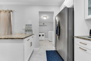 A compact kitchen with white cabinetry, a stainless steel refrigerator, and a built-in oven. - Awesome 3-bedroom house in enchanting Miami Gardens with AC (Miami gardens)