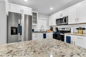A modern kitchen with stainless steel appliances, white cabinetry, and granite countertops. - Awesome 3-bedroom house in enchanting Miami Gardens with AC (Miami gardens)