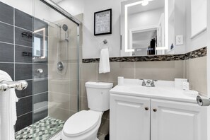 Une salle de bain moderne avec une douche à parois de verre, des toilettes et un lavabo avec un miroir au-dessus.