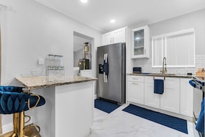 A modern kitchen with white cabinets, a stainless steel refrigerator, and a marble countertop. - Awesome 3-bedroom house in enchanting Miami Gardens with AC (Miami gardens)