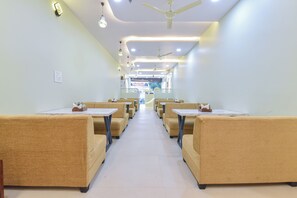 A restaurant with booths and tables, ceiling fans, and recessed lighting. - Hotel Gold Coin (Jaipur)