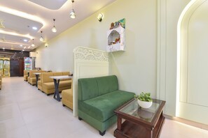 Un vestíbulo de hotel con zonas de estar, un mostrador de recepción y un elemento decorativo en la pared.