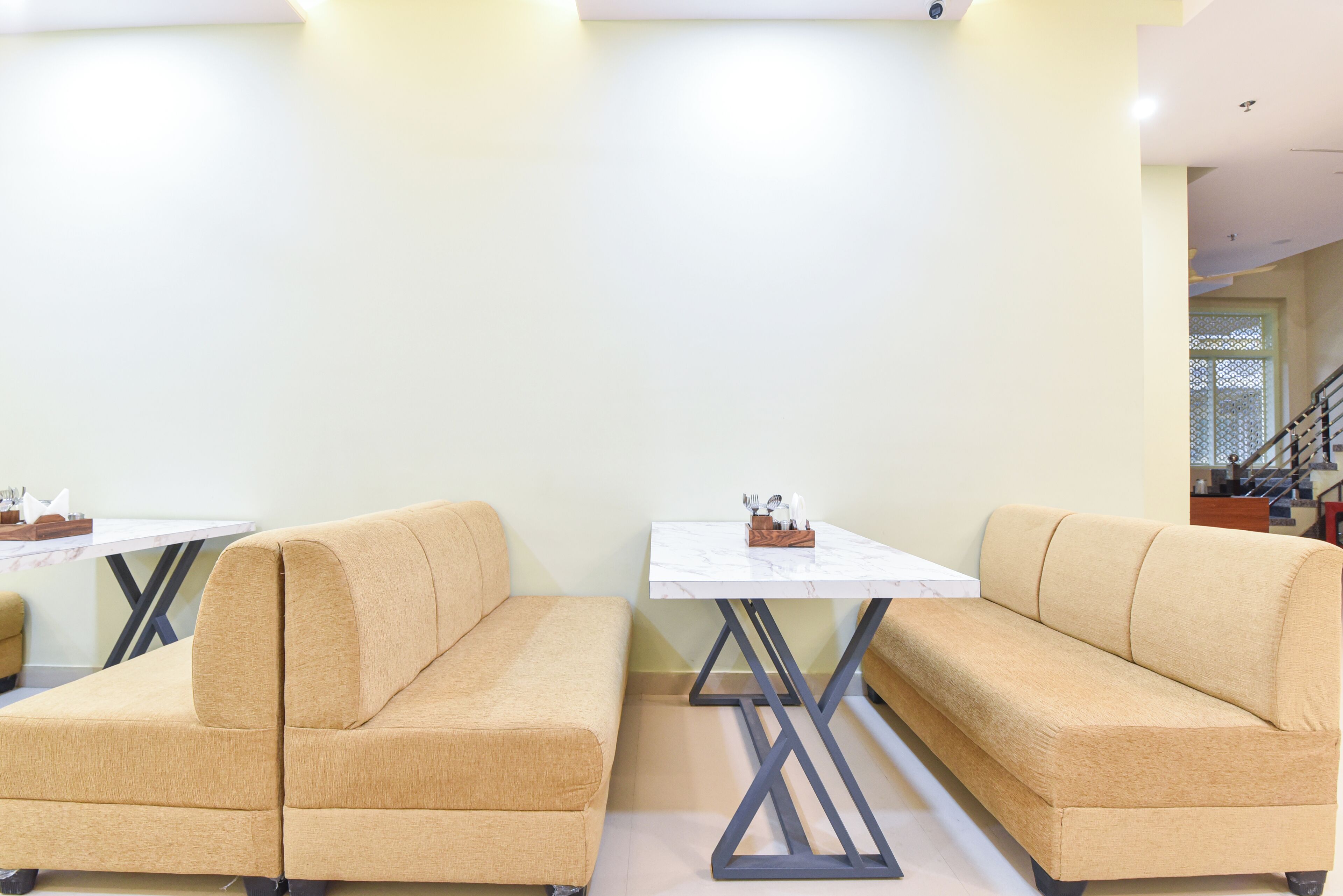 A modern interior with beige sofas, a white table, and a staircase in the background.