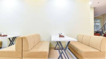 A modern interior with beige sofas, a white table, and a staircase in the background.