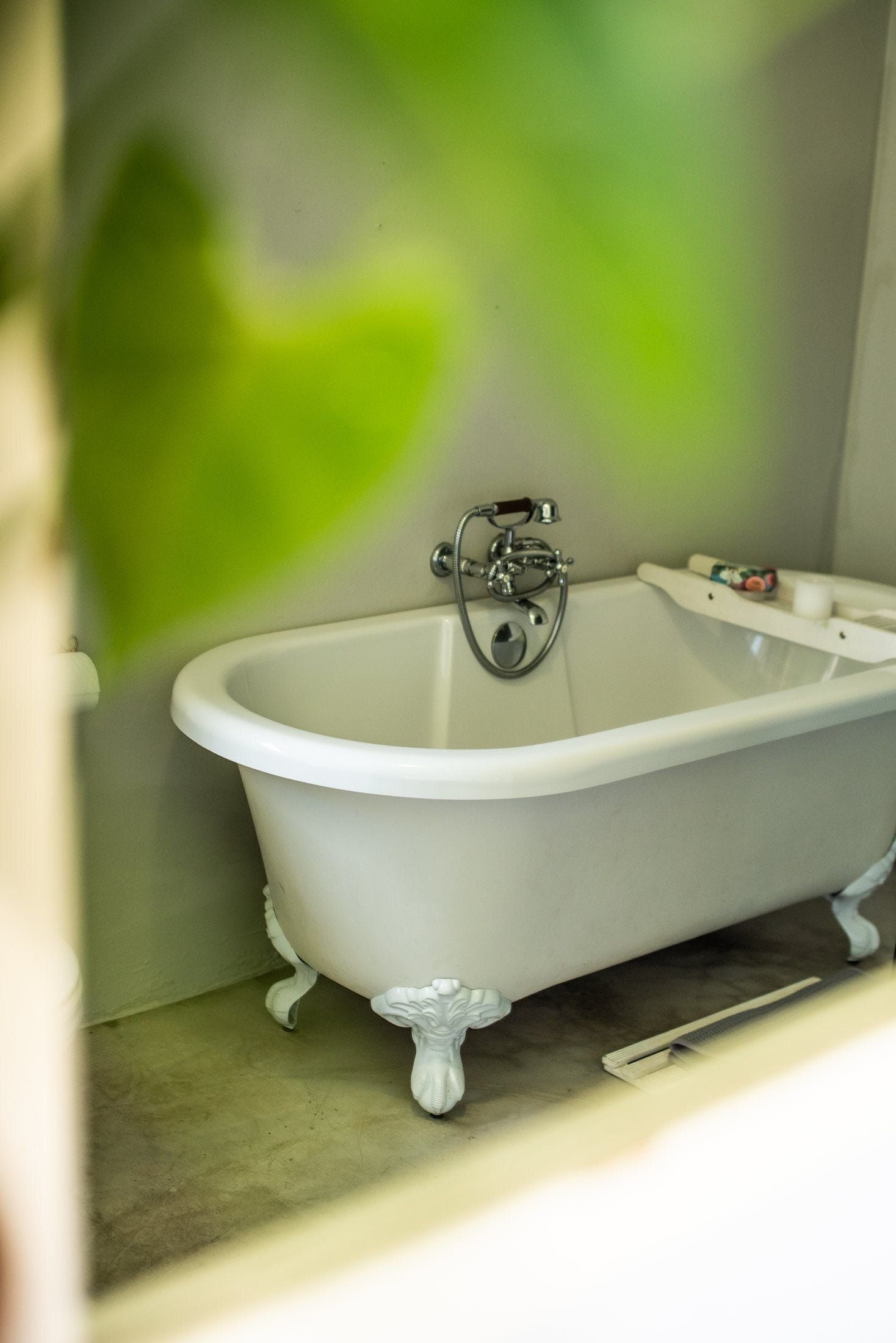 A white clawfoot bathtub with a shower attachment in a bathroom.
