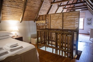 A room with a bed, a hanging clothes rack, and a wooden ceiling structure. - Landmeterskop (Stanford)
