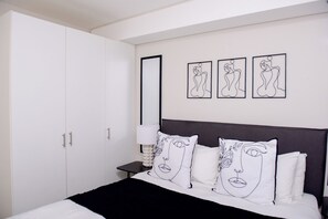 Een hotelkamer met een bed, een nachtkastje, een lamp en drie ingelijste kunstwerken aan de muur.