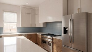 A modern kitchen with stainless steel appliances, a large island, and blue-tiled backsplash. - The Estate | BRAND-NEW 2 Luxury Homes • Connected Backyards • Walk to Beach (Santa Rosa Beach)