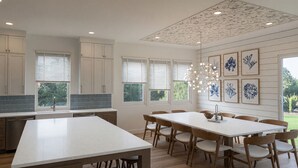 Una cocina moderna con una isla central, sillas de madera y una mesa de comedor.