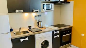 A compact kitchen with a washing machine, a microwave, and a sink.