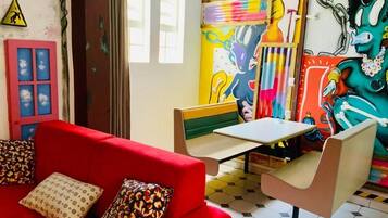 A room with a red sofa, a small table, and a colorful mural on the wall.