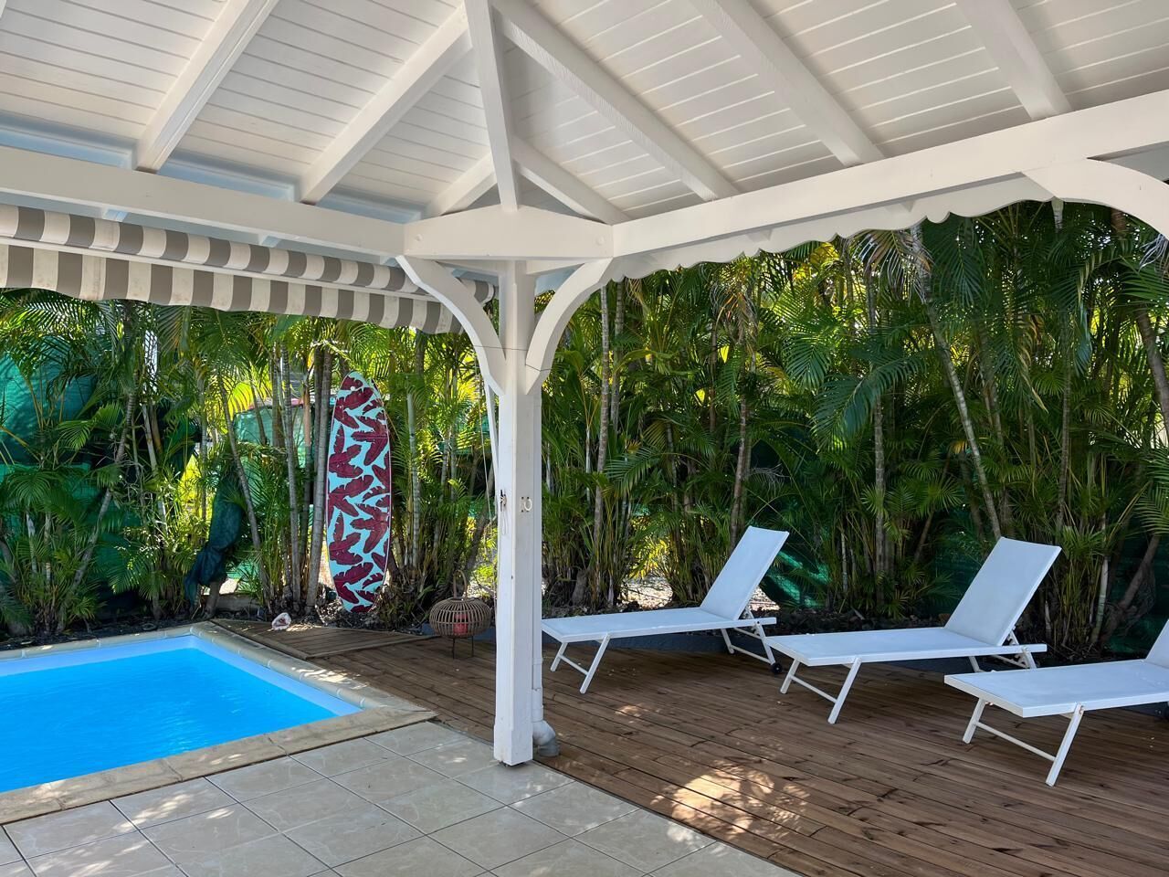 Un área de piscina techada con sillones de descanso y una tabla de surf.
