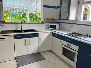 A kitchen with a gas stove, microwave, sink, and cabinets. - Villa Ti-Coco with a private pool (Saint-François)