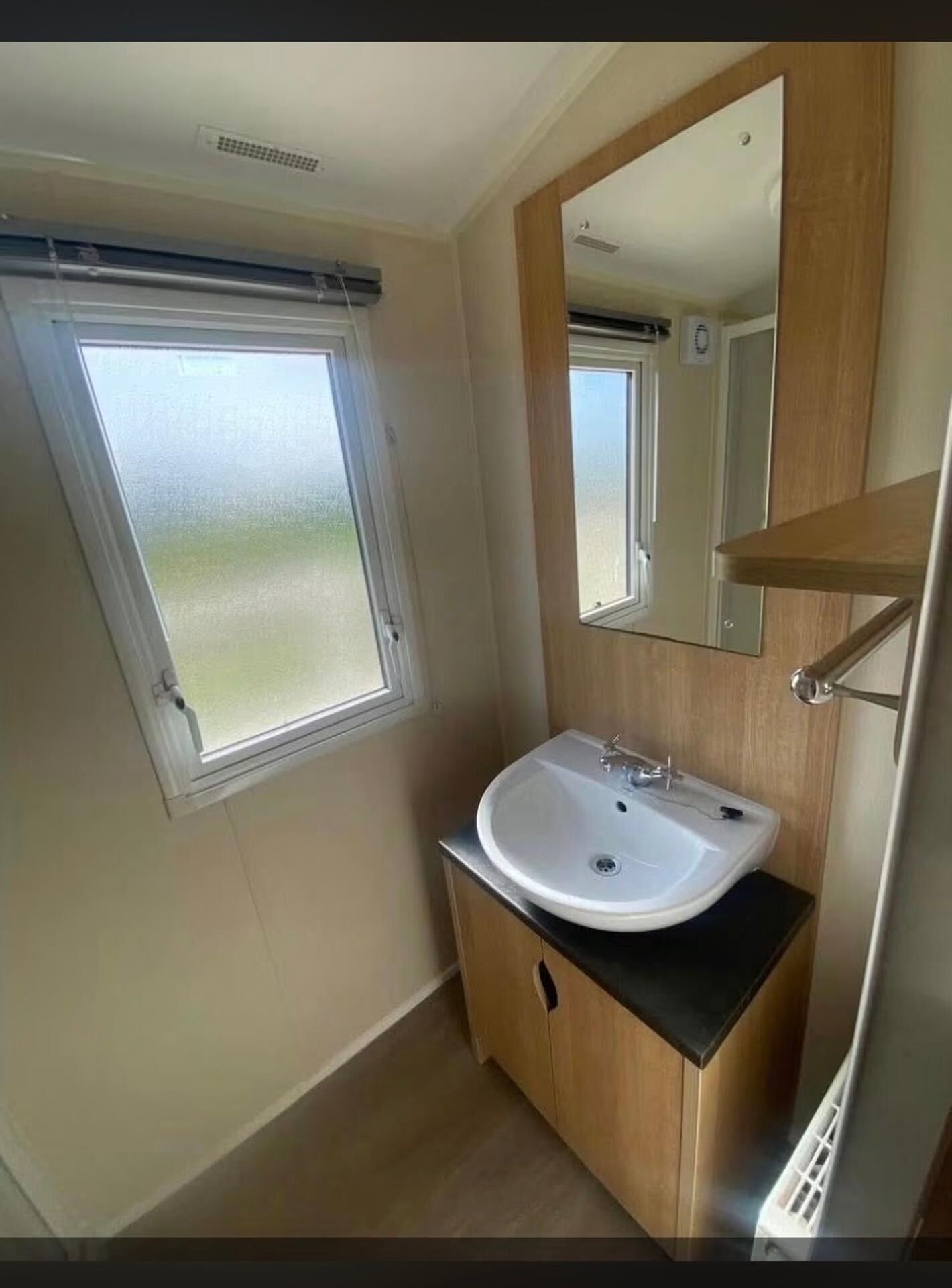 A bathroom with a window, a sink, and a mirror.