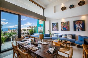 Un vaste espace de vie comprenant une table à manger pour quatre personnes, un canapé et un balcon offrant une vue sur la ville.