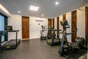 A fitness room with treadmills, a stair climber, and a wall-mounted air conditioning unit. - Romantic Zone 2BR Penthouse | Ocean Views & Pool (Puerto Vallarta)