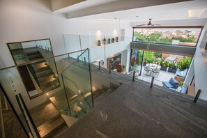 Un intérieur moderne avec un escalier en verre, un coin repas doté d’un espace extérieur et une vue sur le paysage urbain.
