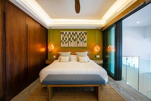 A modern hotel room with a large bed, wooden headboard, and a view of the city through a large window. - Romantic Zone 2BR Penthouse | Ocean Views & Pool (Puerto Vallarta)