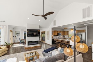 A modern living room with a fireplace, a dining area, and a kitchen. - New Listing, Private Pool, Hot Tub, Walk to Beach, Dogs Welcome C0919 (Corolla)