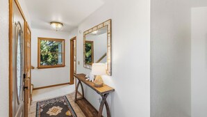 A hallway with a wooden floor, a rug, a console table with a lamp, and a mirror on the wall. - New Listing, Private Pool, Hot Tub, Walk to Beach, Dogs Welcome C0919 (Corolla)