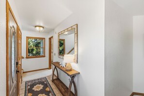 A hallway with a wooden floor, a rug, a console table with a lamp, and a mirror on the wall. - New Listing, Private Pool, Hot Tub, Walk to Beach, Dogs Welcome C0919 (Corolla)
