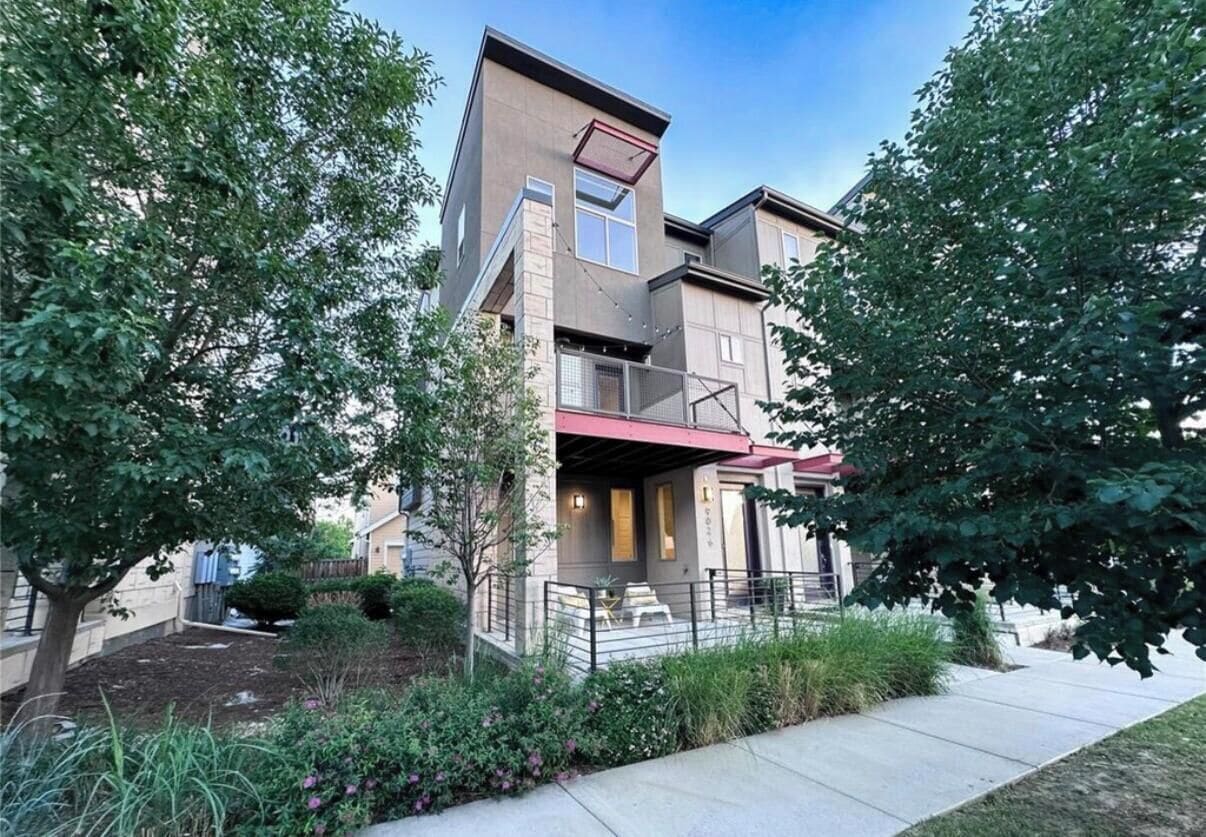 A multi-story residential building with a covered outdoor seating area and a landscaped garden.