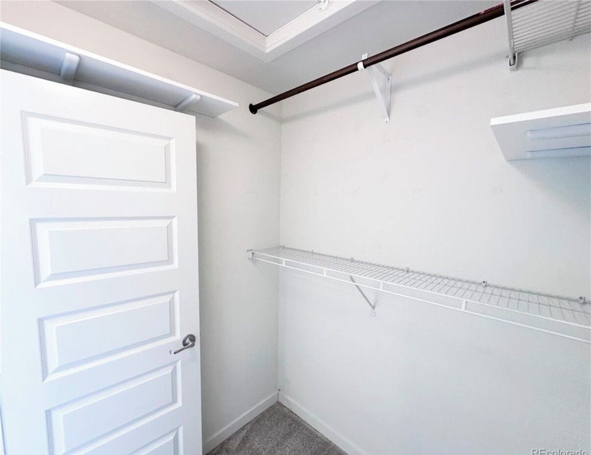 A white door with a handle, a white wall, and a metal shelf.