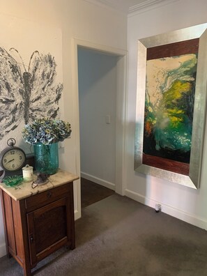 A hallway with a clock, a vase, and a painting on the wall. - Peaceful Hamptons spacious light filled charm. 5min walk shops, parks transport (Kooyong)