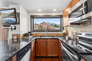 A modern kitchen with a built-in oven, microwave, and a large window offering a view of a mountain and buildings. - Ski-Inspired Mountain Getaway Steps from Peak 9 and Main Street! (Breckenridge)
