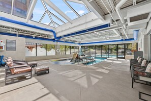 A pool area with lounge chairs, a glass ceiling, and a view of the outside. - Ski-Inspired Mountain Getaway Steps from Peak 9 and Main Street! (Breckenridge)