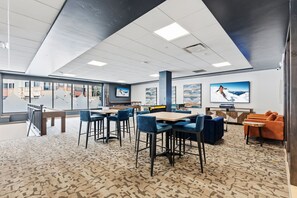 A modern indoor space with a high ceiling, large windows, and a mix of seating areas including tables and chairs. - Ski-Inspired Mountain Getaway Steps from Peak 9 and Main Street! (Breckenridge)