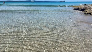 A beach with clear shallow waters and two sailboats in the distance. - Authentic Sardinian house 100 m from the sea (Carloforte)