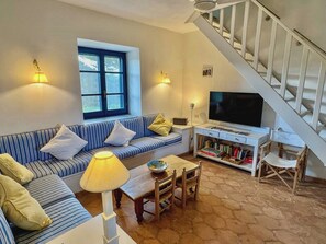 A living room with a sofa, a television, a lamp, and a bookshelf.