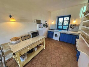 A compact kitchen with a washing machine, a toaster, a microwave, and a sink. - Authentic Sardinian house 100 m from the sea (Carloforte)