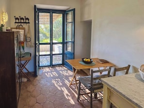 A small kitchen with a table and chairs, a refrigerator, and a door leading to an outdoor area.