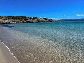 A beach with clear water, a rocky shoreline, and a clear sky. - Authentic Sardinian house 100 m from the sea (Carloforte)