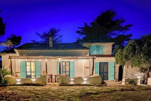 A two-story house with a patio area, a dining table, and chairs. - Authentic Sardinian house 100 m from the sea (Carloforte)