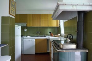 Een compacte keuken met houten kastjes, een witte vaatwasser en een spoelbak.