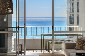 A balcony with a view of the ocean, a sofa, and a table with chairs. - Wake to stunning ocean views from this modern Surfers Paradise apartment. Enjoy a private balcony, resort pool, spa, kids playground, and tennis court, with the beach, Cavill Avenue, shopping and dining all just a short walk away. (Surfers Paradise)