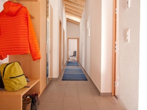 A hallway with a blue carpet, wooden walls, and a door at the end. - Powder Snow Loft - by Zermatt Apartment Rentals : Matterhorn Views, sleeps 6-7 (zermatt)