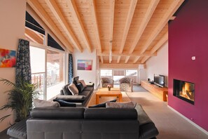 A modern living room with a wooden ceiling, a fireplace, a sofa, and a television. - Powder Snow Loft - by Zermatt Apartment Rentals : Matterhorn Views, sleeps 6-7 (zermatt)