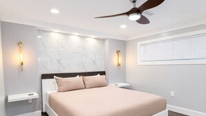 Una camera da letto moderna con un letto grande, una ventola a soffitto e illuminazione a parete.